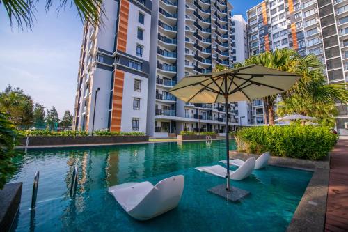 a swimming pool with chairs and an umbrella at Timurbay by Seascape in Kuantan