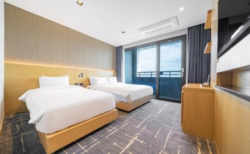 um quarto de hotel com duas camas e uma televisão em Sea Cruise Hotel em Sokcho