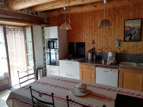 una cocina con electrodomésticos blancos y una mesa en una habitación en Maison typique pleine de charme Peyrusse Cantal, en Peyrusse