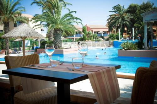 - une table avec des verres à vin en face de la piscine dans l'établissement Superbe appartement au calme proche de la plage, à Canet