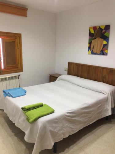 Un dormitorio con una cama blanca con toallas verdes. en Apartamento González Montsec Montrebei, en Tolva