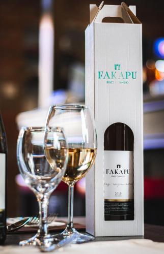 two glasses of white wine next to a wine box at Fakapu Pince és Panzió in Tokaj