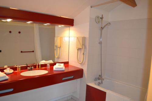 uma casa de banho com um lavatório, um espelho e uma banheira em Noemys Gradignan - ex Cit'Hotel Le Chalet Lyrique em Gradignan