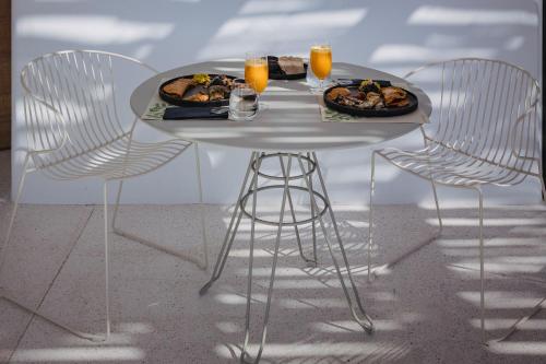 a white table with two chairs and a plate of food at Koukoumi Vegan Boutique Hotel in Ano Mera