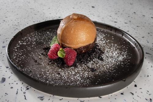 a chocolate dessert with strawberries on a black plate at Koukoumi Vegan Boutique Hotel in Ano Mera