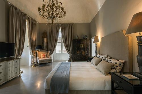a large bedroom with a large bed and a chandelier at Seven Rooms Villadorata in Noto