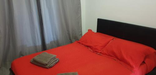 1 cama roja con almohada roja y 2 toallas en Piso Vista Oceano Cristiano III, en Playa de las Américas