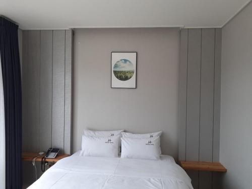 a bedroom with a white bed and a picture on the wall at Tongyeong Bridge Hotel in Tongyeong