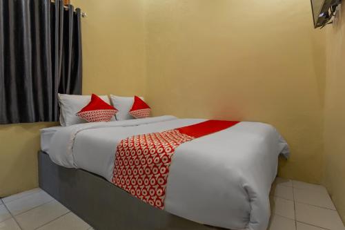 a bedroom with a bed with red and white pillows at OYO 2527 Hotel Triana in Palangkaraya