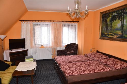 a bedroom with two beds and a television and a chandelier at Penzion Dřevěnka in Osečná