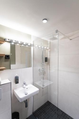 a white bathroom with a sink and a shower at Munich Rooms Hotel in Munich