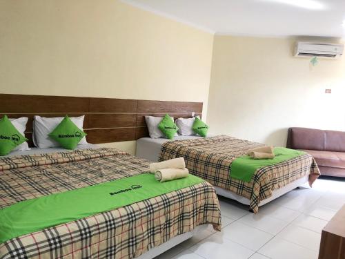 um quarto de hotel com duas camas com lençóis verdes em Bamboe Inn Homestay em Bandar Lampung