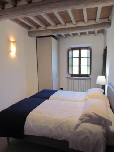 a bedroom with a bed with white sheets and a window at Podere La Casa in Villa dʼArceno