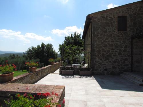 a stone building with a patio with plants and flowers at Podere La Casa in Villa dʼArceno