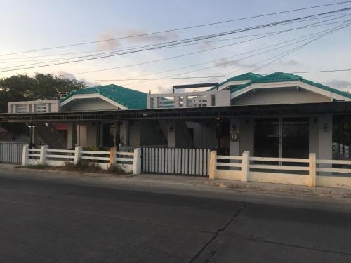 a house with a white fence next to a street at Sealife Private Beach Villa in Ban Nong Si Tong