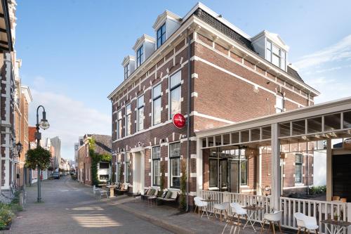 a brick building with tables and chairs on a street at Boutique Hotel - de Stadsherberg Alphen in Alphen aan den Rijn
