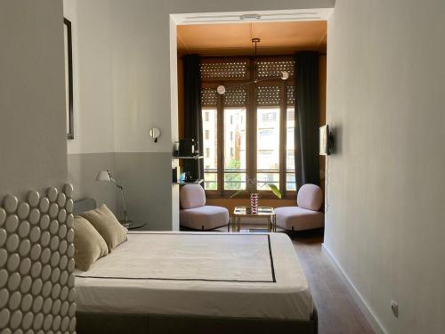 a bedroom with a bed and two chairs and a window at BUBUFLATS Ayuntamiento in Valencia