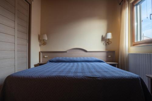 a bedroom with a blue bed and a window at Hotel Don Giovanni in Ururi