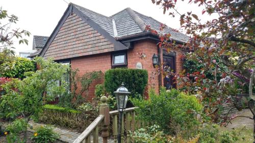 a red brick house with a wooden fence at Hollingworth Lake Guest House Room Only Accommodation in Littleborough