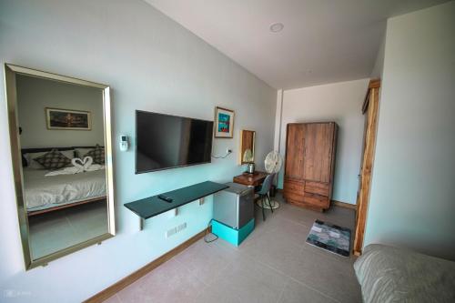 1 dormitorio con TV, escritorio y cama en Lotus Lake View en Ban Bua