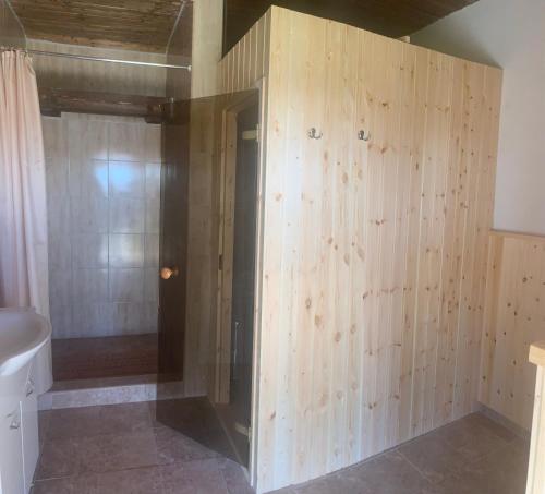 a bathroom with wooden walls and a shower stall at Pillangó Vendégház in Tállya