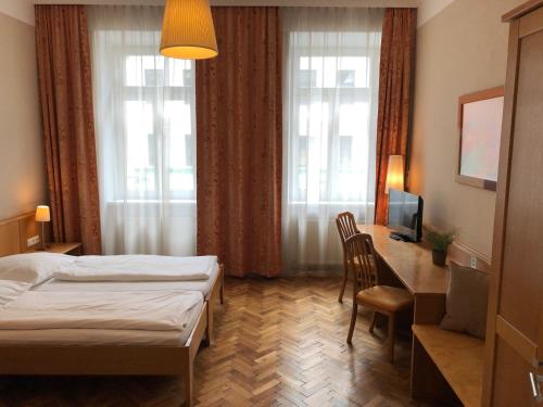 a hotel room with a bed and a desk and window at Gasthof Schwabl Wirt in Vienna