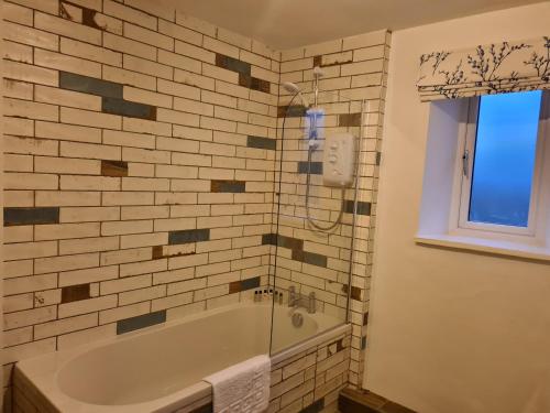 a bathroom with a tub and a glass shower at Derwentwater Arms in Curbar