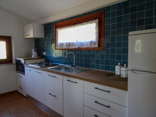 eine Küche mit weißen Schränken, einer Spüle und grünen Fliesen in der Unterkunft Casa Rita in Costa Paradiso