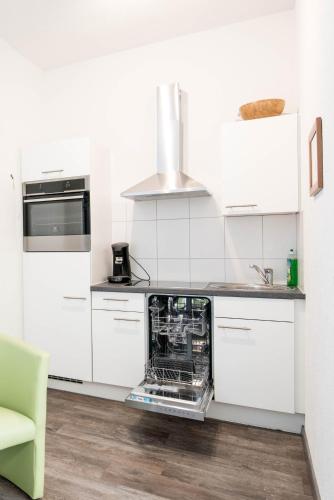 a white kitchen with an open dishwasher in the middle at Apartmenthaus Aalen in Aalen