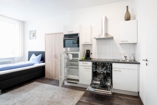 a kitchen with white cabinets and a stove top oven at Apartmenthaus Aalen in Aalen