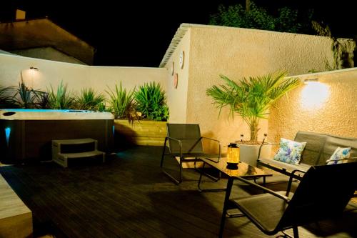 a patio with chairs and tables and a hot tub at Le petit paradis in Orange