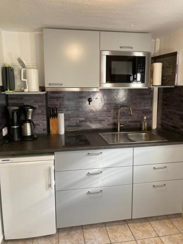 a kitchen with white cabinets and a sink and a microwave at Ferienwohnung Flecken Zechlin in Flecken Zechlin