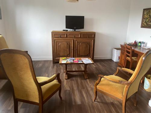 - un salon avec des chaises, une table et une télévision dans l'établissement Bel appartement à GRANVILLE 50400 partagé avec GERARD Minimun 2 nuits, à Saint-Nicolas-près-Granville