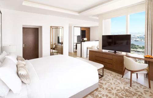 a white bedroom with a large bed and a flat screen tv at Sofitel Dubai The Obelisk in Dubai