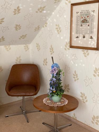 a chair and a table with a vase of flowers on it at Ferienwohnung Paulina in Braunschweig