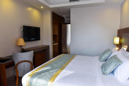 a hotel room with a bed and a television at Admas Grand Hotel in Entebbe
