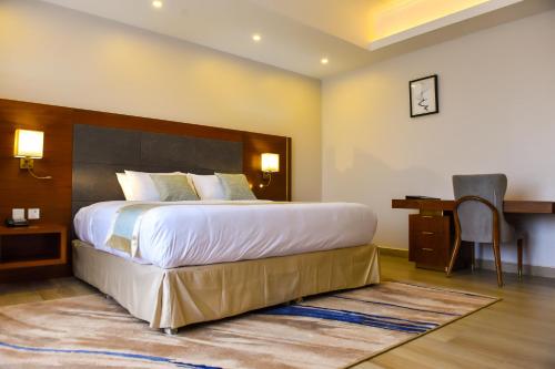 a hotel room with a large bed and a desk at Admas Grand Hotel in Entebbe