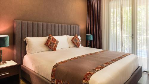 a bedroom with a large bed with a large window at Kabira Country Club in Kampala