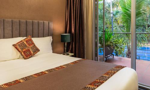a hotel room with a bed and a balcony at Kabira Country Club in Kampala