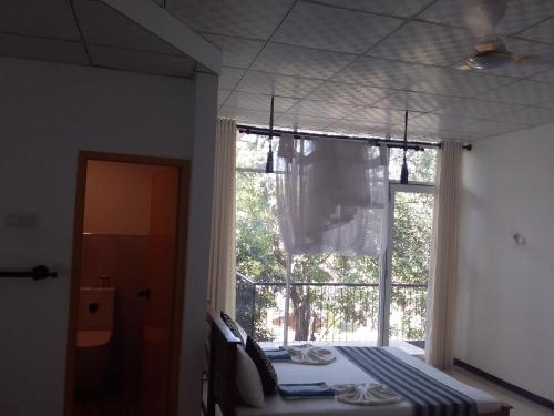 a bedroom with a bed and a large window at Sudunelum Holiday Resort in Anuradhapura