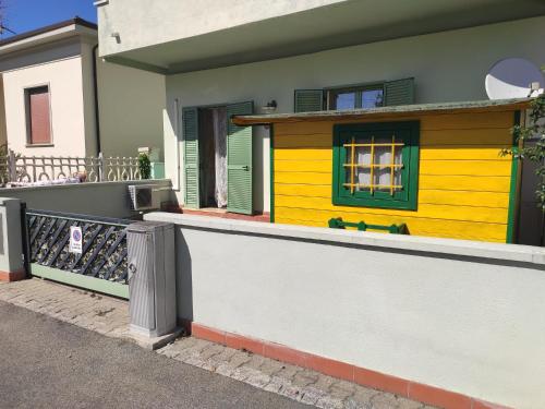 dom z żółtymi i zielonymi drzwiami i płotem w obiekcie La casina di Anna w mieście Vecchiano