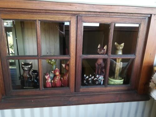 a wooden cabinet with a bunch of cat figurines in it at Kattekwaad Accommodation in Kaapsehoop