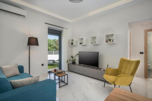 een woonkamer met een tv en een bank en stoelen bij Nectar Luxury Residence in Kissamos