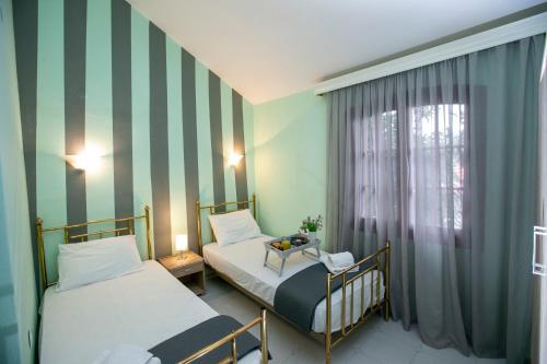 2 camas en una habitación con rayas verdes y blancas en Villa Kouf, en Nea Iraklitsa