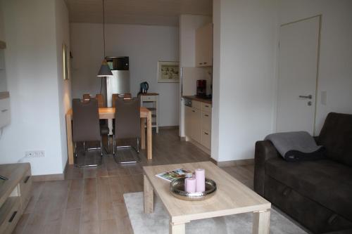 a living room with a table and a couch and a kitchen at Haus Wanderlust in Willingen