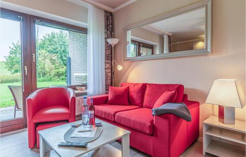 a living room with a red couch and a table at Awesome Apartment In Friedrichskoog in Friedrichskoog