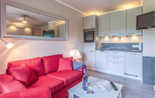 a living room with a red couch and a kitchen at Awesome Apartment In Friedrichskoog in Friedrichskoog