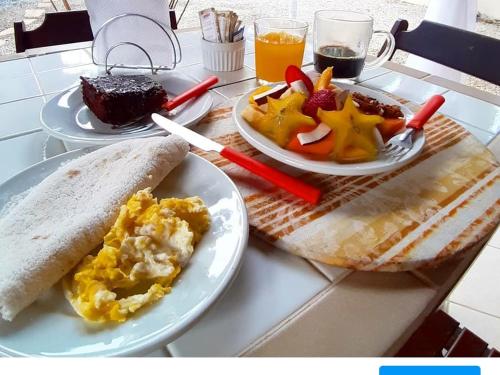 a table with two plates of breakfast food on it at Itamambuca Casa de Praia in Ubatuba