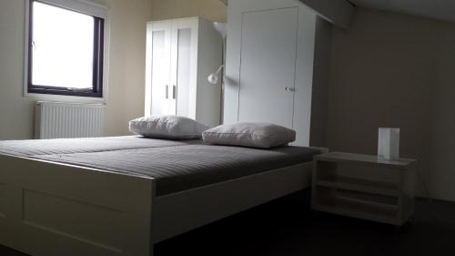 a bedroom with a bed with two pillows on it at Vakantie studio Heeg met eigen ligplaats in Heeg