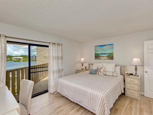 1 dormitorio con 1 cama y balcón en Luxury Waterfront Views - Heated Pool - 1400sf Duplex - Minutes to the Beach, en Siesta Key